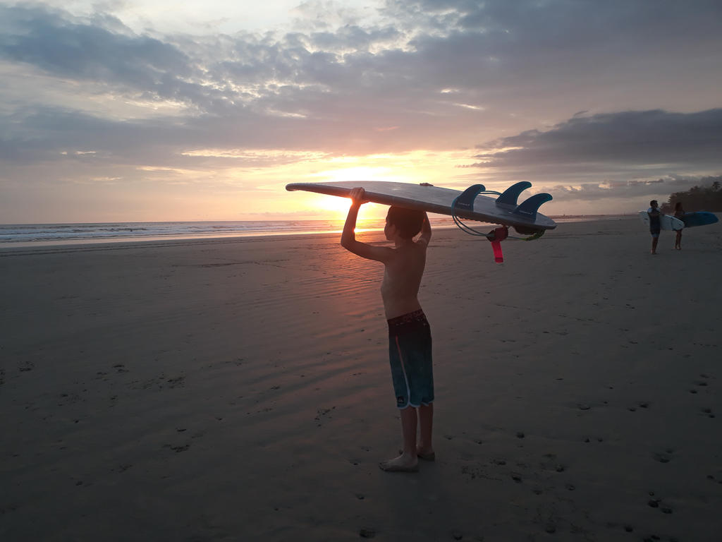 Oskar i solnedgangen med surfboard på hovedet