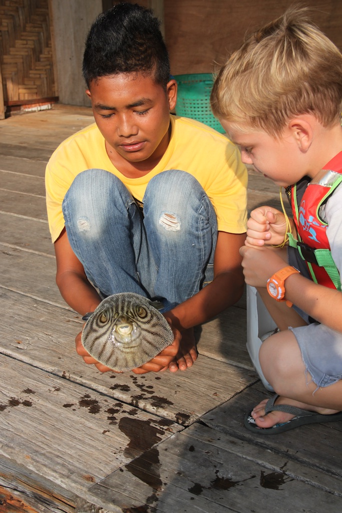 Oskar og malaysisk dreng der viser en oppustet pufferfish frem på fiskefarmen
