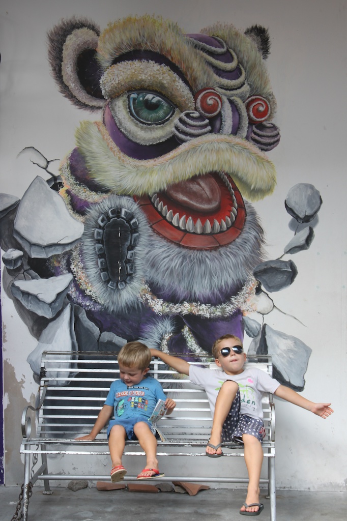 Alfred og Oskar på en bænk foran et vægmaleri i George Town