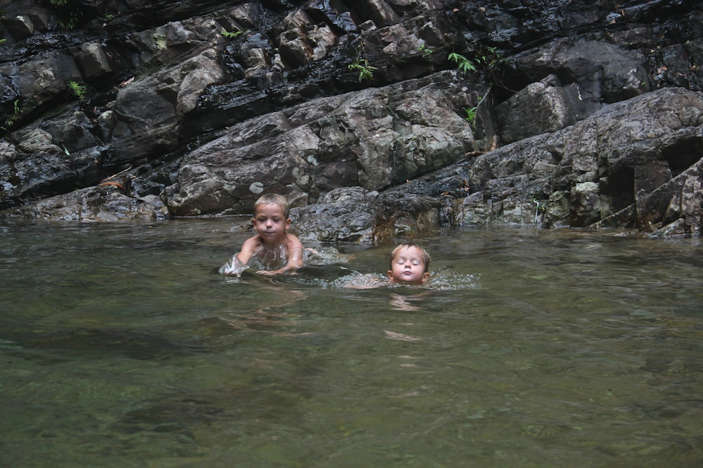 Oskar og Alfred svømmer i det kølige vand i poolen under Temurun vandfaldet