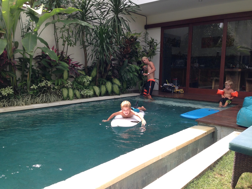 Oskar padler på surfbræt i poolen i Villa Cendana