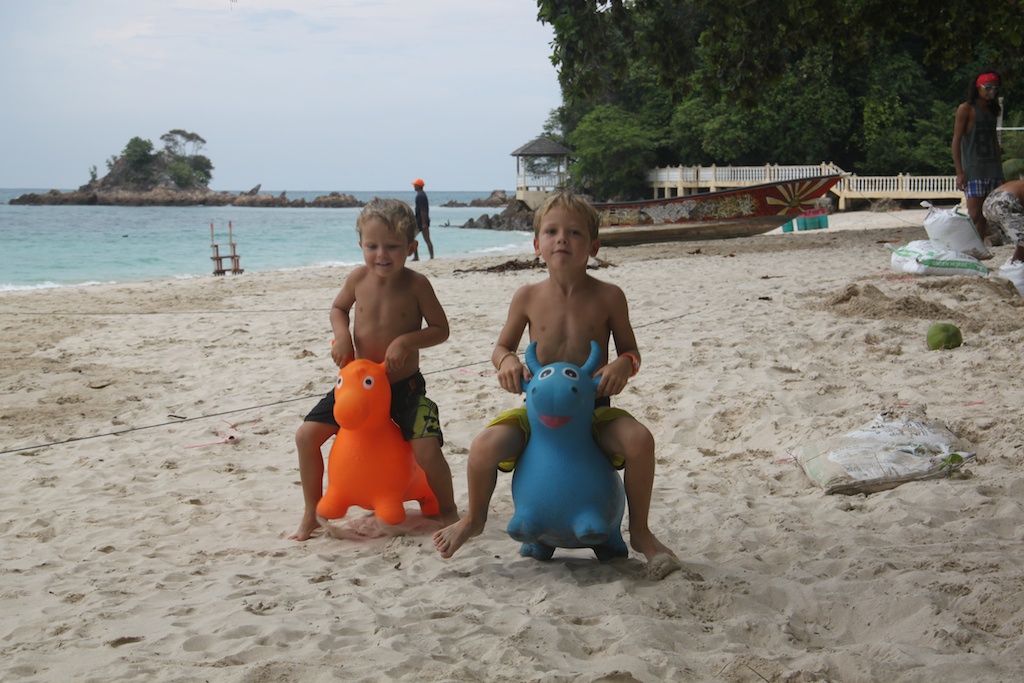 Alfred og Oskar på hoppedyr på stranden foran Kapas Beach Chalets