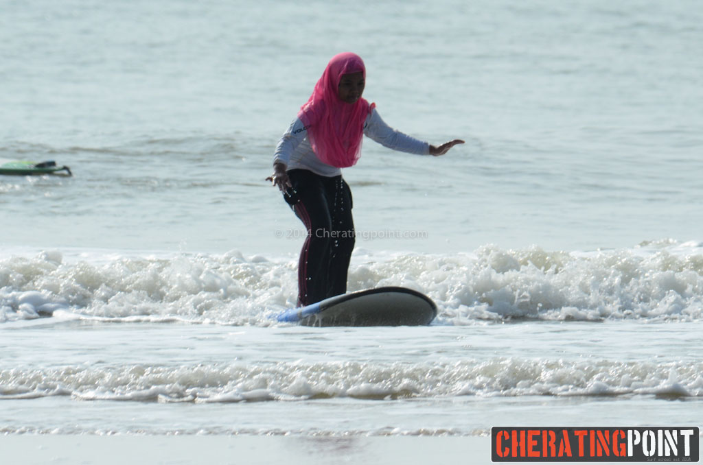 Kvindelig malaysisk surfer iført lange bukser trøje og tørklæde