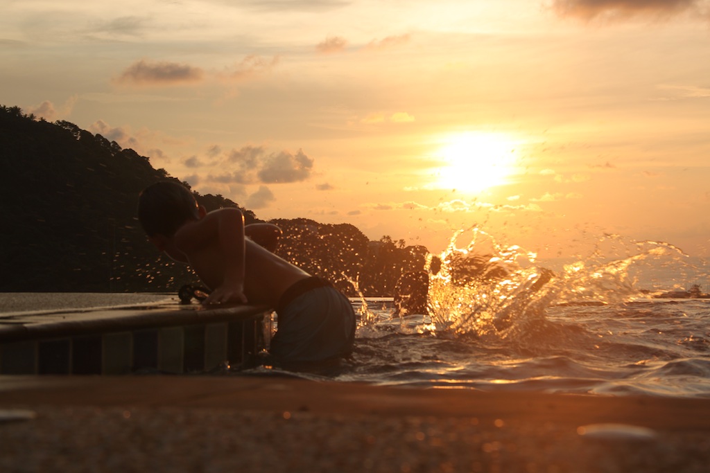 Alfred plasker baglæns i poolen i solnedgangen mens Oskar kravler op