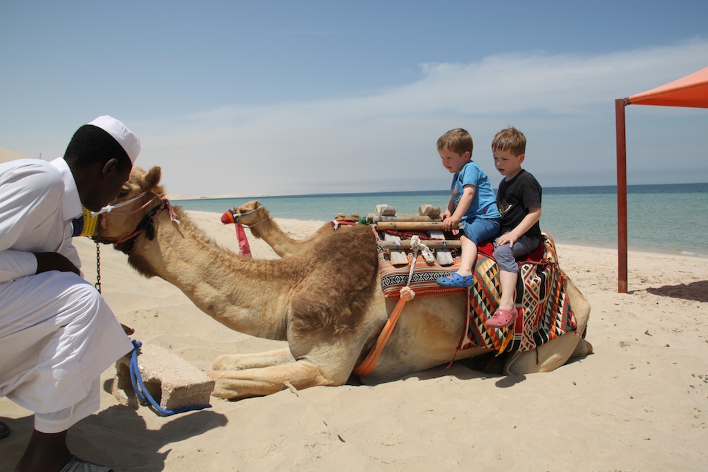Alfred og Oskar på kamel på stranden i Qatar