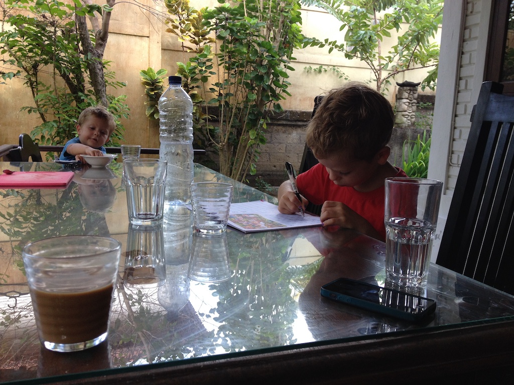 Oskar tegner og Alfred spiser ved vores udendørs spisebord