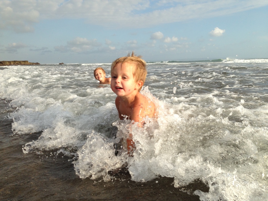 Alfred og Oskar svømmer i bølgerne ved Echo Beach