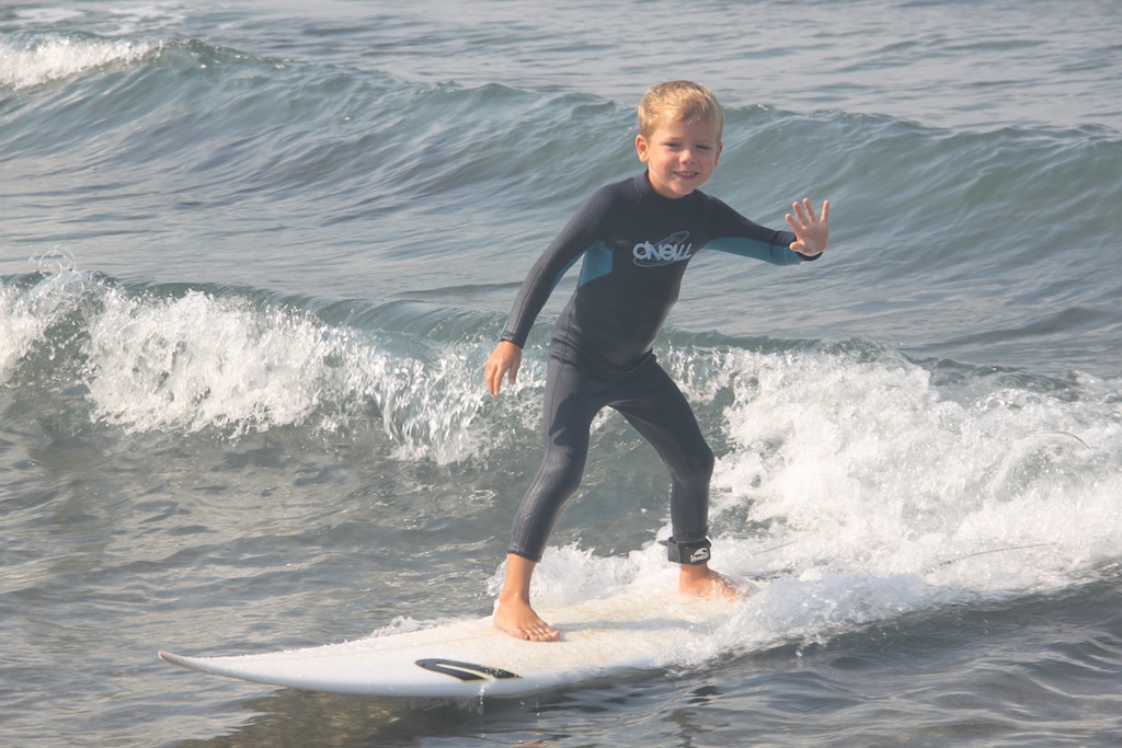 Oskar surfer på Rasmus' shortboard og vinker til kameraet