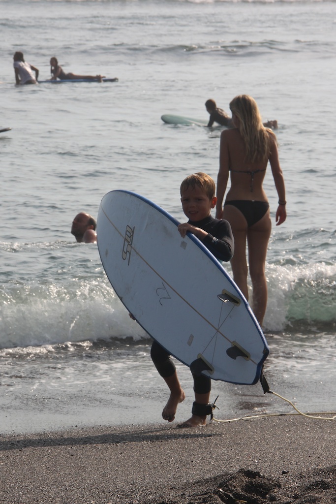 Oskar bærer et surfbræt i vandkanten